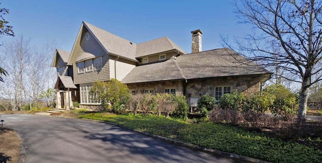 view of side of property featuring stone siding and a chimney