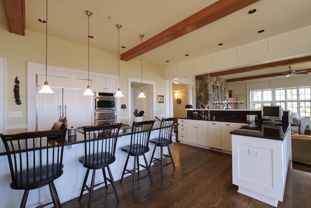 kitchen with beamed ceiling, white cabinets, dark countertops, dark wood-style floors, and stainless steel oven