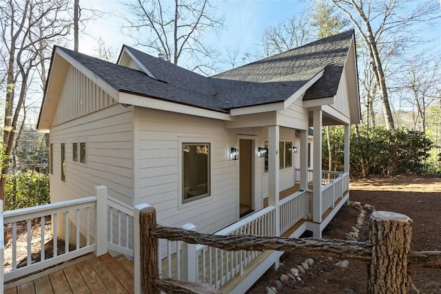 exterior space with board and batten siding, roof with shingles, a porch, and a deck