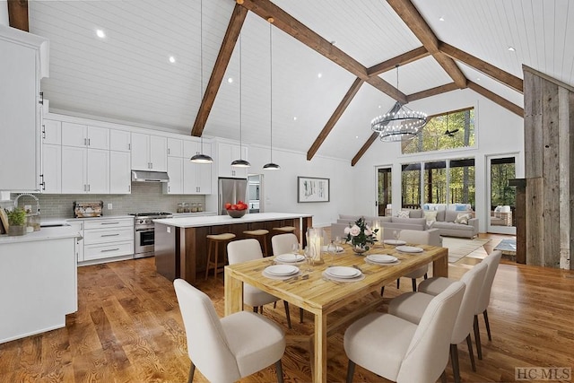 dining area featuring sink, high vaulted ceiling, dark hardwood / wood-style flooring, a notable chandelier, and beam ceiling