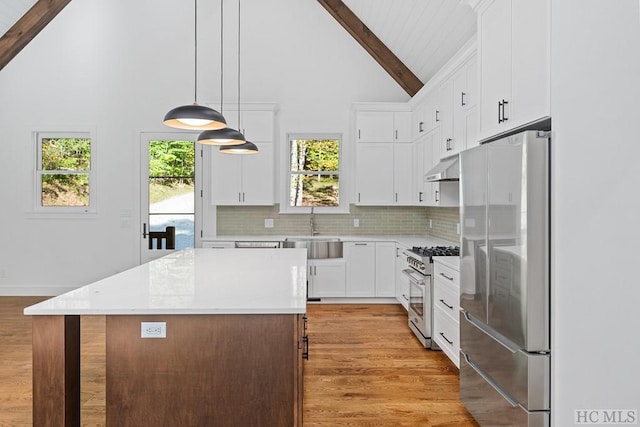 kitchen featuring decorative light fixtures, appliances with stainless steel finishes, a kitchen island, beamed ceiling, and white cabinets