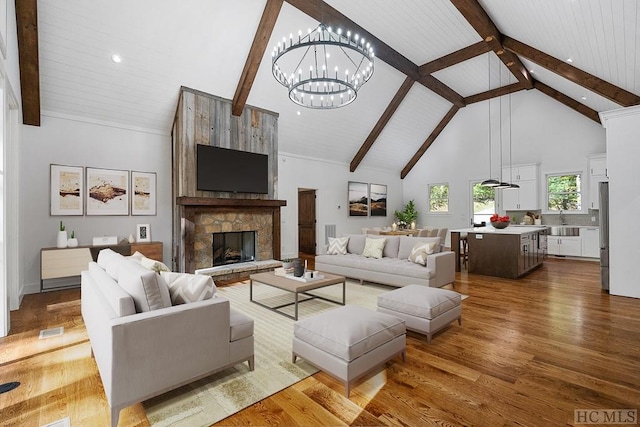 living room with sink, an inviting chandelier, wood-type flooring, high vaulted ceiling, and a fireplace