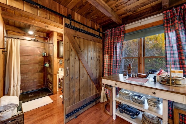 interior space with hardwood / wood-style floors, wooden walls, wooden ceiling, and a barn door