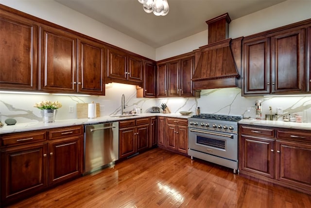 kitchen with sink, appliances with stainless steel finishes, dark hardwood / wood-style floors, custom range hood, and decorative backsplash