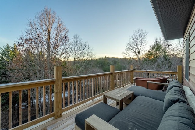 deck at dusk featuring a hot tub