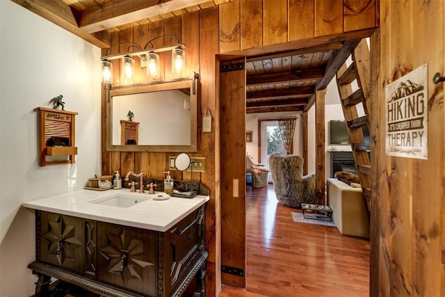 bathroom featuring wooden walls, beamed ceiling, wood-type flooring, vanity, and wooden ceiling