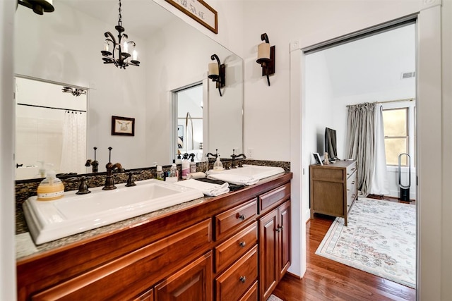 bathroom featuring hardwood / wood-style flooring, vanity, lofted ceiling, and an inviting chandelier