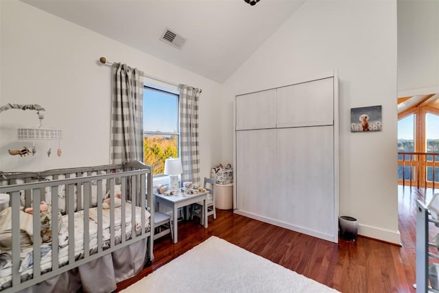 bedroom featuring a nursery area, dark hardwood / wood-style floors, and vaulted ceiling