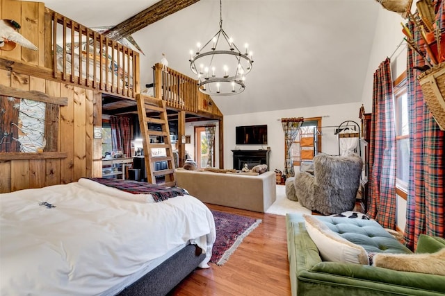 bedroom with multiple windows, hardwood / wood-style flooring, a chandelier, and wooden walls