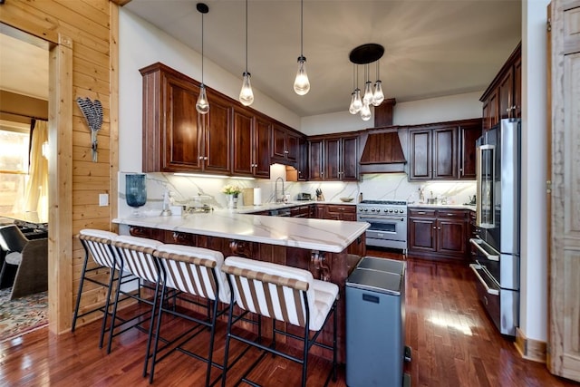 kitchen with premium appliances, custom exhaust hood, a kitchen breakfast bar, and hanging light fixtures