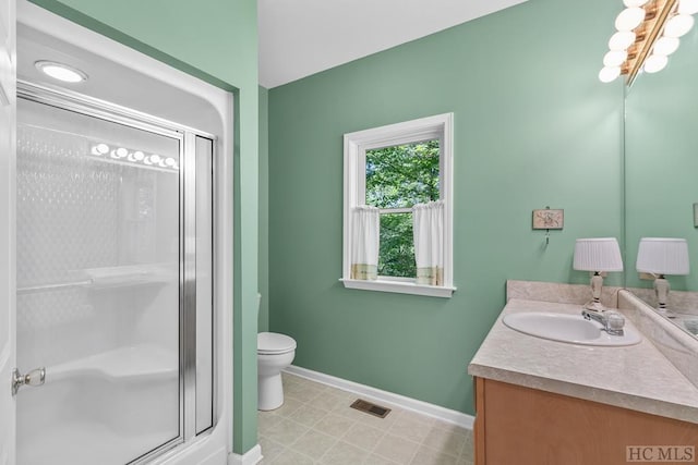 bathroom with an inviting chandelier, vanity, toilet, and a shower with door