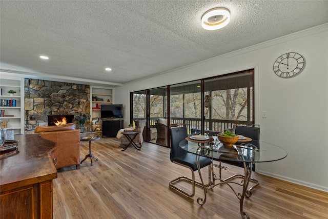 home office featuring a textured ceiling, crown molding, a fireplace, wood finished floors, and baseboards