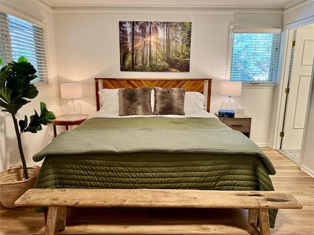 bedroom with baseboards, ornamental molding, and light wood finished floors