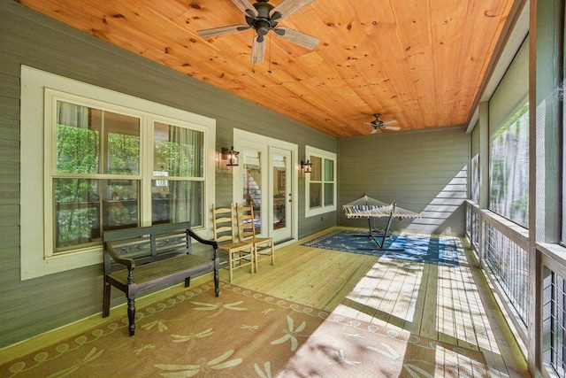 sunroom featuring a ceiling fan, wood ceiling, wood finished floors, and wooden walls