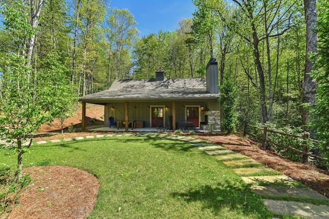 rear view of property with a chimney, board and batten siding, and a porch