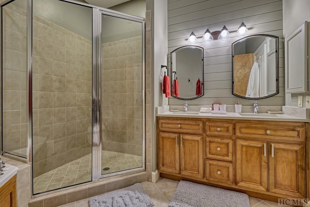 bathroom featuring tile patterned flooring, vanity, wooden walls, and walk in shower