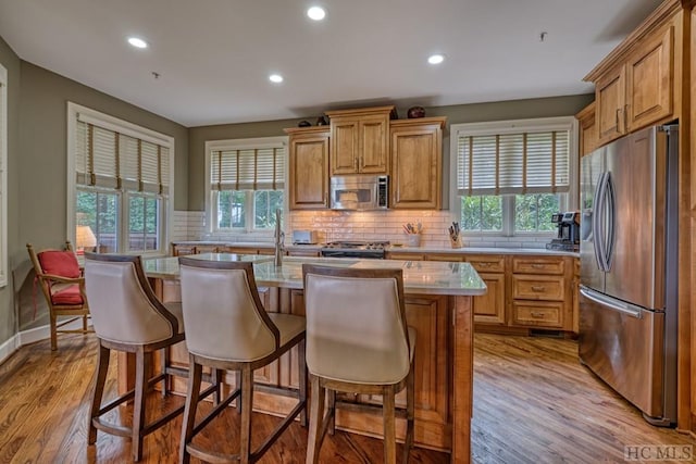 kitchen featuring stainless steel appliances, a kitchen island, a healthy amount of sunlight, and light hardwood / wood-style floors