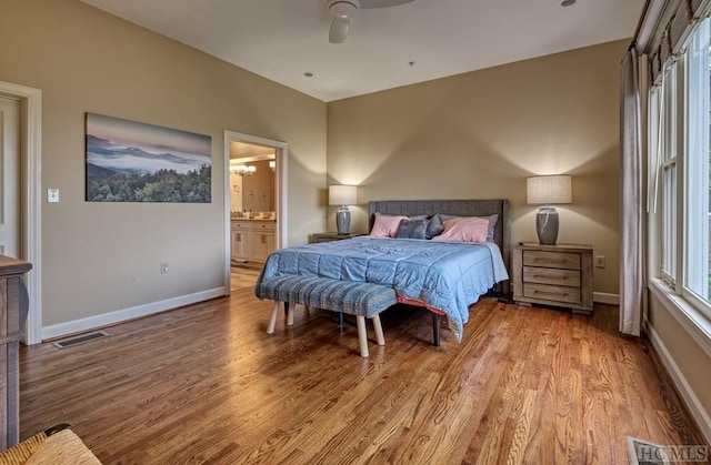 bedroom with ceiling fan, ensuite bathroom, and light wood-type flooring