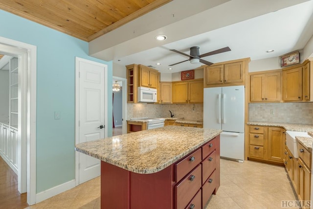 kitchen with light stone counters, white appliances, a kitchen island, and open shelves