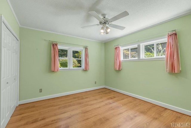 unfurnished bedroom with a closet, ornamental molding, ceiling fan, light wood-type flooring, and baseboards