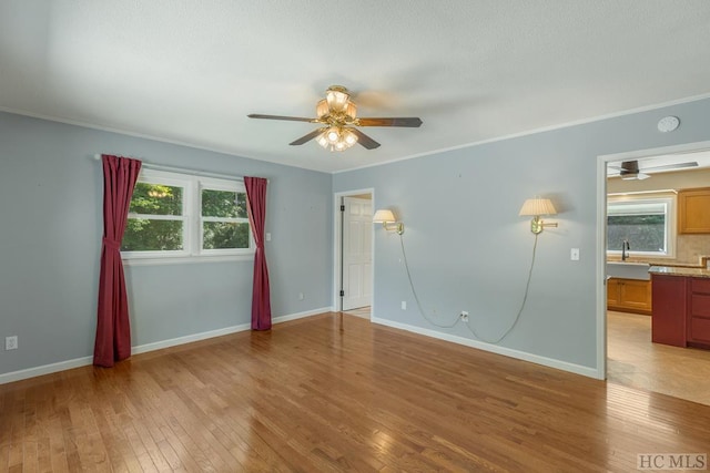 unfurnished bedroom featuring light wood-style flooring, crown molding, baseboards, and a sink