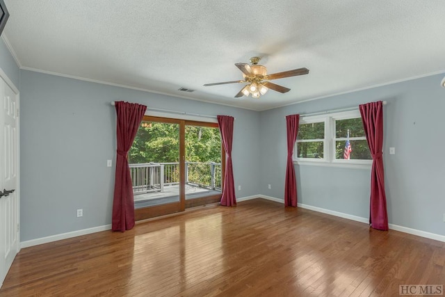 spare room featuring visible vents, a textured ceiling, baseboards, and wood finished floors