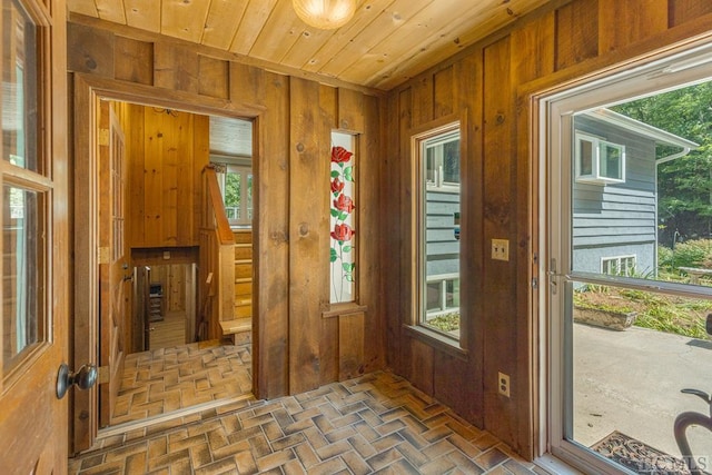 doorway to outside with brick floor, wood ceiling, and wooden walls