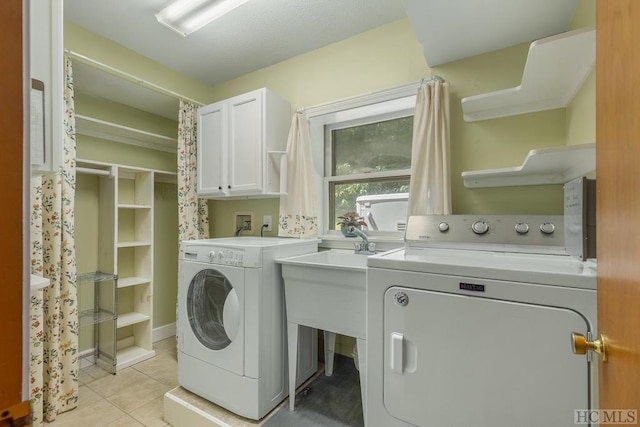 laundry room featuring cabinet space, light tile patterned floors, and washer and clothes dryer