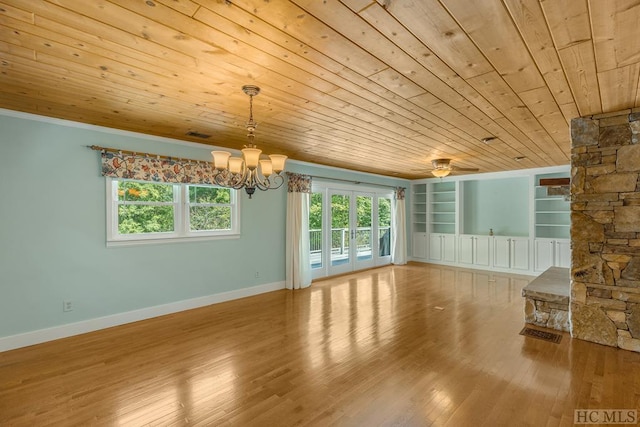 unfurnished living room featuring built in shelves, a notable chandelier, wood ceiling, wood finished floors, and baseboards