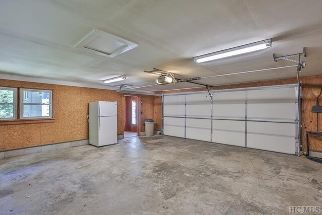 garage featuring freestanding refrigerator and a garage door opener