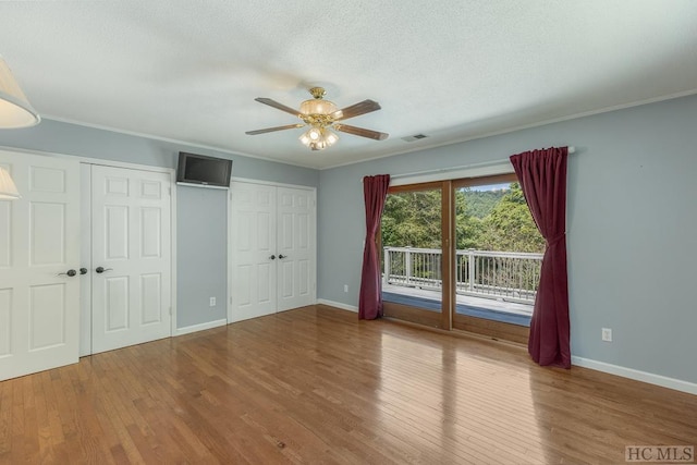 unfurnished bedroom featuring baseboards, wood finished floors, visible vents, and access to exterior