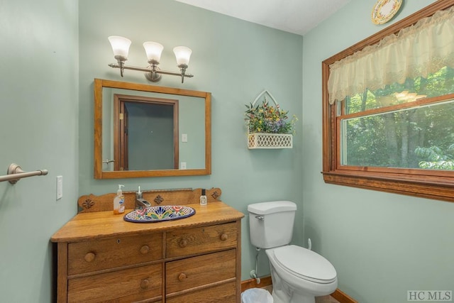 half bathroom featuring toilet, vanity, and baseboards