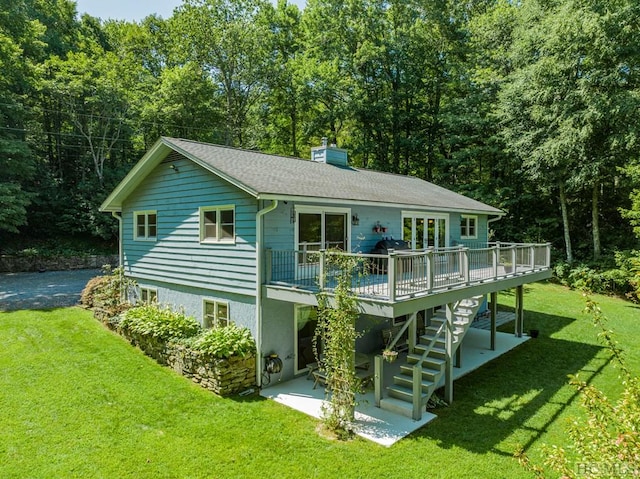 rear view of property with stairway, a lawn, a chimney, and a wooden deck