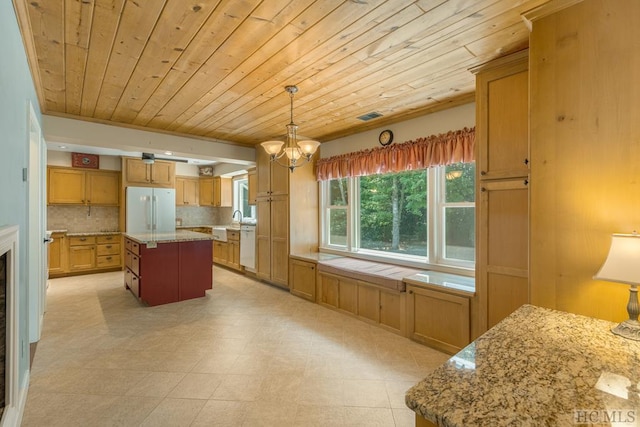 kitchen with a chandelier, white appliances, hanging light fixtures, a center island, and tasteful backsplash