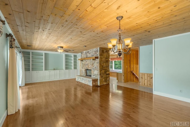 unfurnished living room featuring built in shelves, wooden ceiling, light wood-style floors, and a stone fireplace