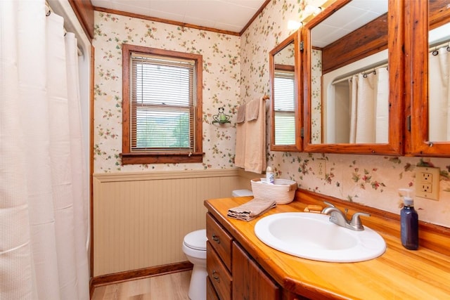 full bathroom with wallpapered walls, wainscoting, toilet, ornamental molding, and vanity