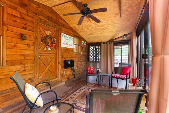 sitting room with lofted ceiling, wood walls, wood finished floors, and a ceiling fan