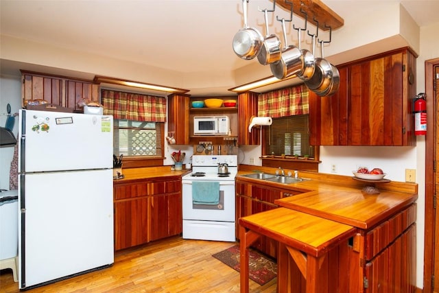 kitchen with white appliances, a sink, light wood-style flooring, and wooden counters