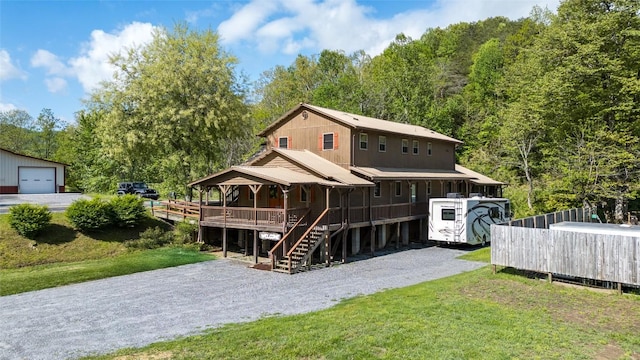 rear view of property with covered porch, stairs, a lawn, and driveway