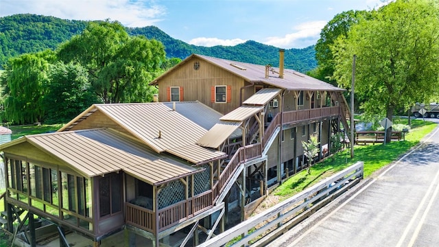 view of side of home featuring a standing seam roof, a mountain view, and metal roof