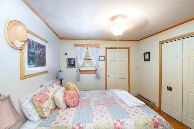 bedroom featuring baseboard heating, ornamental molding, a closet, and wood finished floors