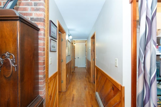 corridor featuring a wainscoted wall, light wood-type flooring, and wood walls