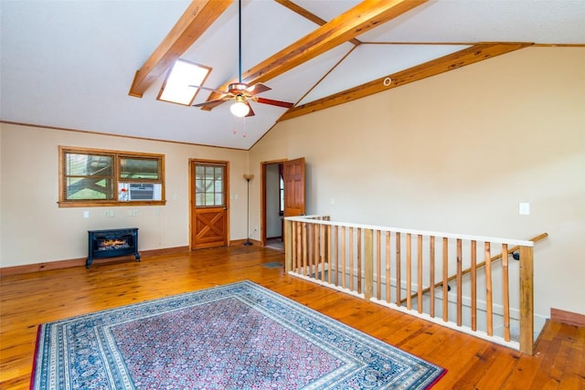 interior space with wood-type flooring, a ceiling fan, beam ceiling, baseboards, and high vaulted ceiling