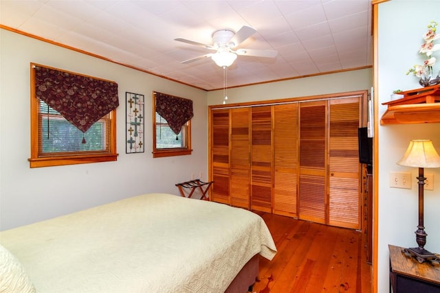 bedroom with hardwood / wood-style floors, crown molding, a closet, and ceiling fan