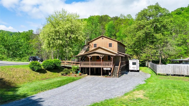 view of front of house featuring driveway, stairway, and a wooded view