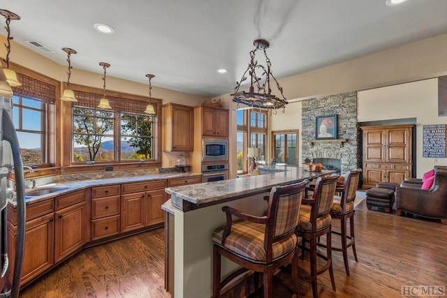 kitchen featuring stainless steel appliances, a kitchen island, hanging light fixtures, and a breakfast bar