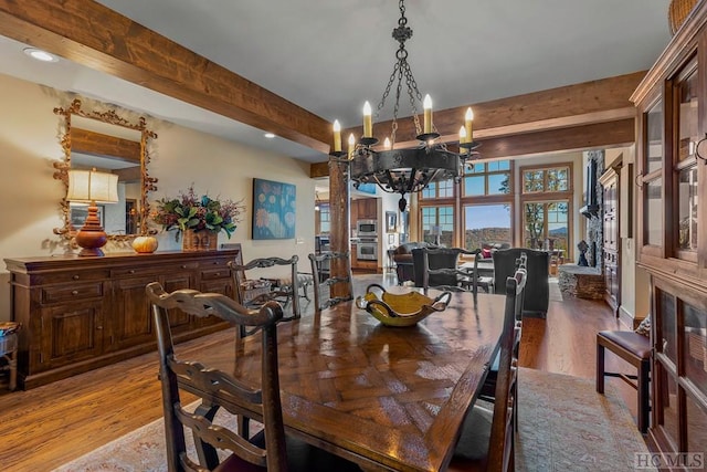 dining space featuring hardwood / wood-style floors, a notable chandelier, and beamed ceiling