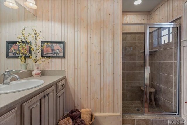 bathroom with walk in shower, vanity, and wood walls