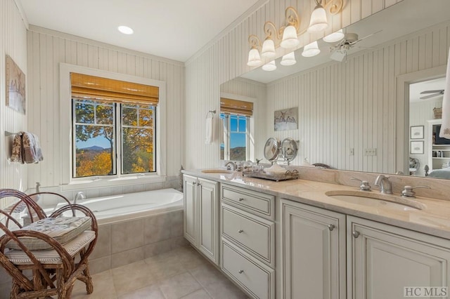 bathroom with tiled tub, vanity, tile patterned floors, and ceiling fan