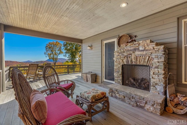 wooden deck with a mountain view and an outdoor stone fireplace